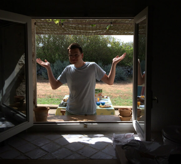 Man shrugging seen through an open window